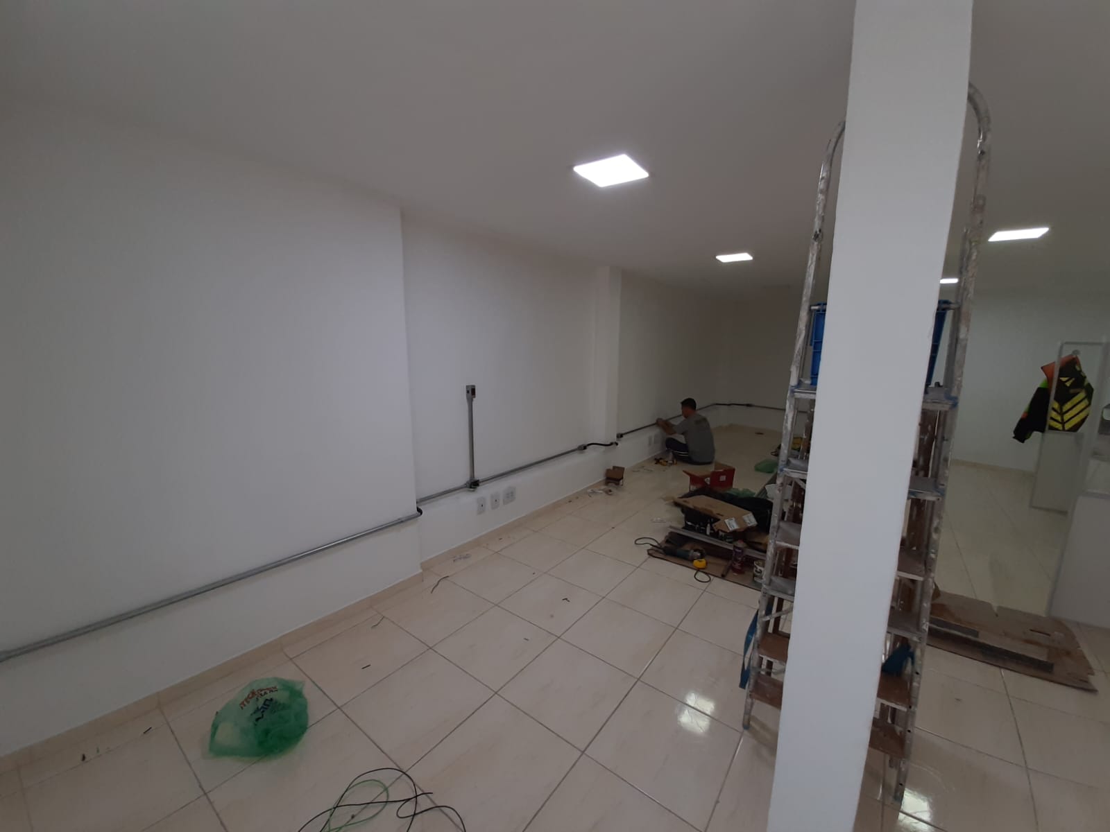 Profissional instalando eletrodutos e pontos elétricos em área comercial